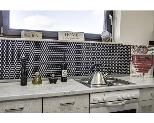 Keukenopstelling met spoelbak, fornuis, kranen en keukengerei tegen een zwarte mozaïekachtergrond