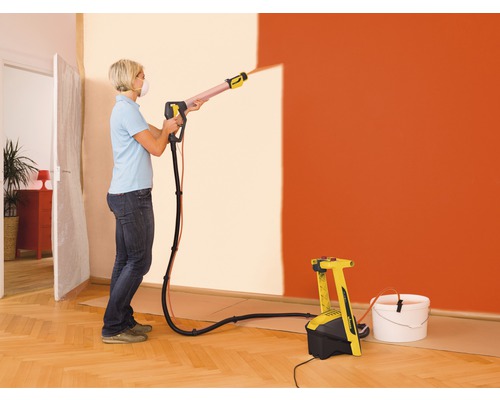Vrouw gebruikt verfspuitsysteem om een muur te schilderen
