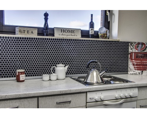 Keukenscène met mozaïektegels, theepot, waterkoker en kookplaat.