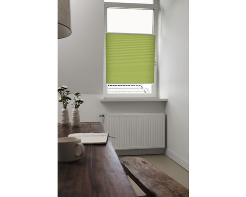 Lichte kamer met harmonicaraam voor het raam, tafel, bank en radiator.