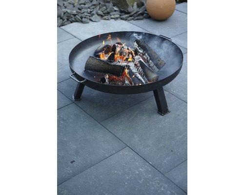 Metalen vuurschaal met brandend hout in de tuin
