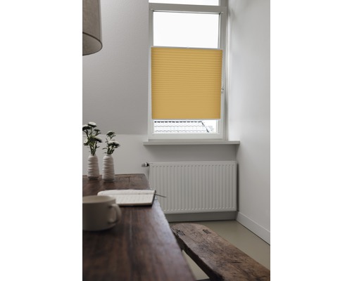 Geel plisségordijn voor het raam in een lichte kamer.