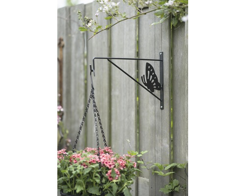 Bloempotbeugel met vlindermotief op een houten schutting