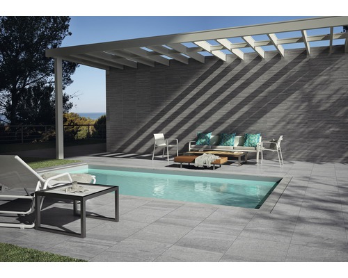 Terras met zwembad, tegelvloer, wandbekleding en zithoek onder een pergola.