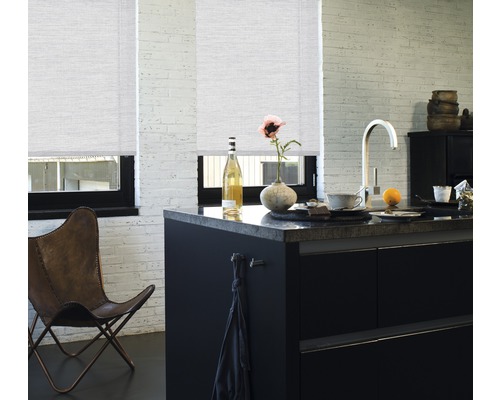 Lichte keuken met twee rolgordijnen voor de ramen, zwart kookeiland en leren stoel