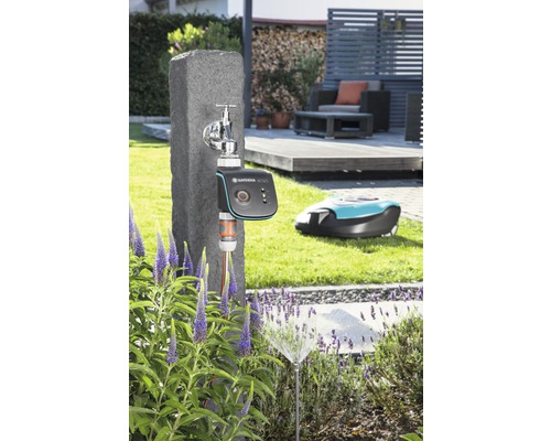 Scene met een kraan, een Gardena besproeiingscomputer, een gazonsproeier en een robotmaaier in de tuin.