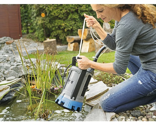Vrouw gebruikt een vuilwaterpomp bij de tuinvijver