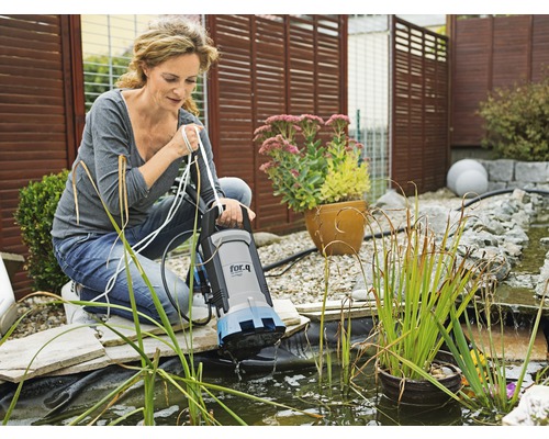 Vrouw gebruikt een for.q vijverpomp in een tuinvijver.