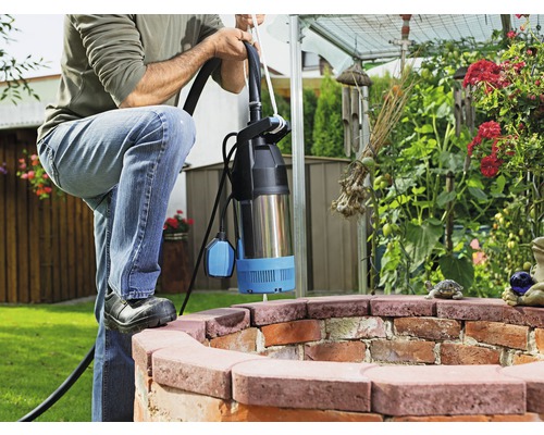 Man met dompelpomp in een tuinbron