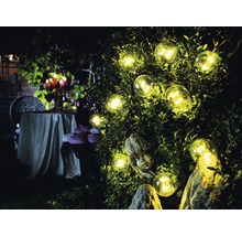 Tuin met verlichte gloeilampen, beeld en tafel met kaarsen