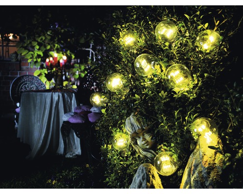 Tuin met verlichte gloeilampen, beeld en tafel met kaarsen