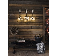 Rustieke houten wanddecoratie met geweien, lichtslingers, bank, deken en houtblokken voor een gezellige sfeer