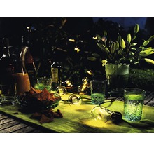 Tafel met drankjes, glazen, snacks en een lichtsnoer in de tuin ''s nachts.