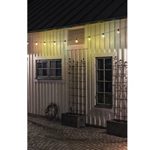 Buitenkant van een huis met lichtsnoer, ramen en plantenbakken.