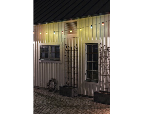 Buitenkant van een huis met lichtsnoer, ramen en plantenbakken.
