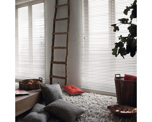 Lichte kamer met witte jaloezieën, ladder en decoratieve elementen.