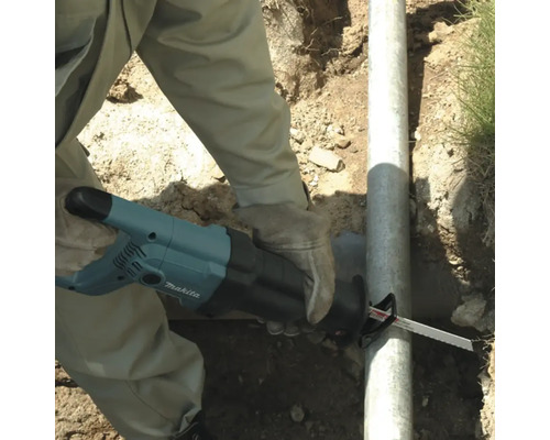 Een persoon zaagt een pijp door met een Makita reciprozaag.