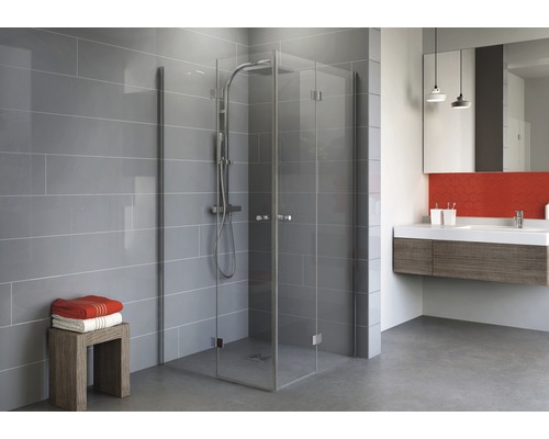 Badkamer met glazen douchecabine, wastafel en grijze tegels.