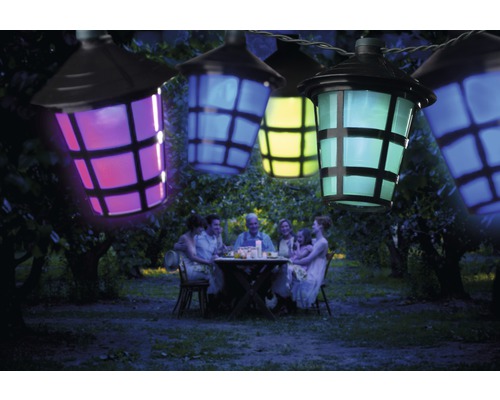 Lichtsnoer met kleurrijke lantaarns boven een gezin dat in de tuin zit