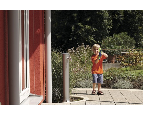 Jongen met waterpistool naast een tuinkraan