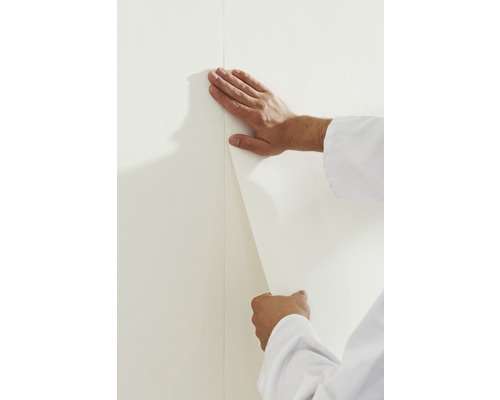 Iemand brengt behang aan op een muur