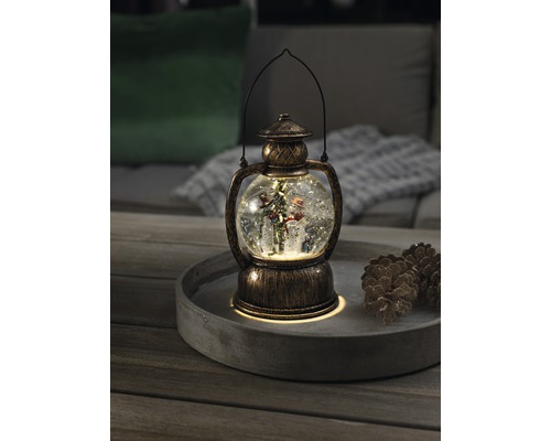 Decoratieve sneeuwbollantaarn met sneeuwpop en kerstboom op een dienblad