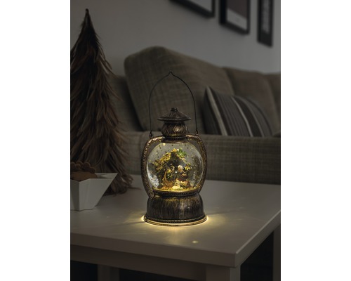 Decoratieve lantaarn met sneeuwbol en kerststal op een tafel