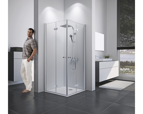 Lichte badkamer met hoekdouche, wastafelonderkast en staande persoon