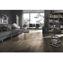 Woonkamer met bank, fauteuil, boekenkast en laminaatvloer.