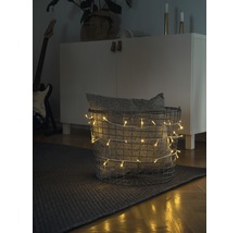 Decoratieve scène met een mand gevuld met een lichtsnoer en een kussen op een vloerkleed