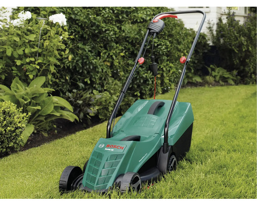 Elektrische grasmaaier op gazon voor struiken