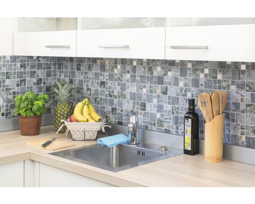 Lichte keuken met mozaïektegels, roestvrijstalen gootsteen en verse ingrediënten.