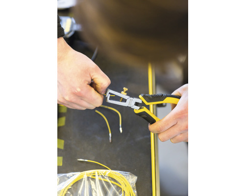 Een persoon gebruikt een striptang op een gele kabel.