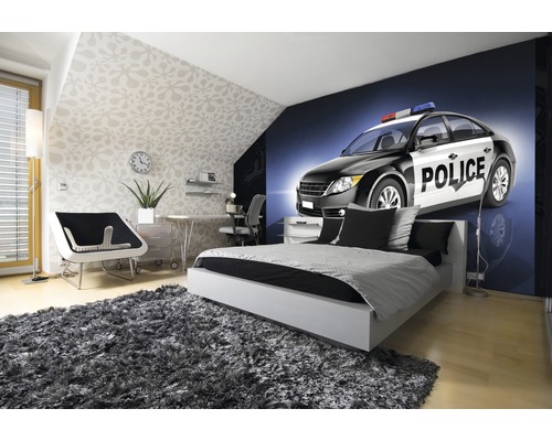 Lichte slaapkamer met bed, bureau en fotobehang van een politieauto