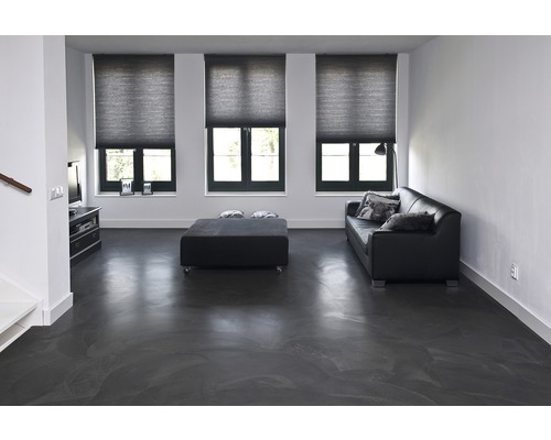 Lichte woonkamer met bank, tafel en rolgordijnen voor de ramen.