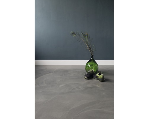 Een kamer met een grijze vloer, een groene glazen vaas met pauwenveren en schoenen.