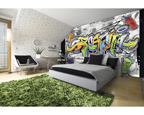 Moderne slaapkamer met graffitibehang, bed, bureau en groen tapijt.