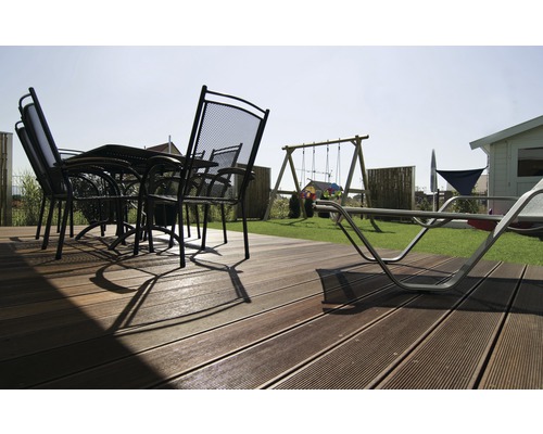 Terras met terrasplanken, tuintafel, stoelen en speelplaats in de tuin.