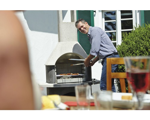 Man grilt vlees met een barbecue tang op een tuingrill.