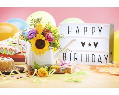 Decoratief verjaardagsarrangement met gieter, bloemen, cadeaus en lichtbak