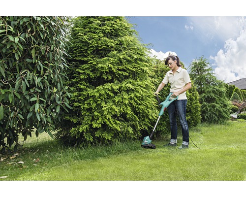 Vrouw gebruikt gazontrimmer in de tuin.