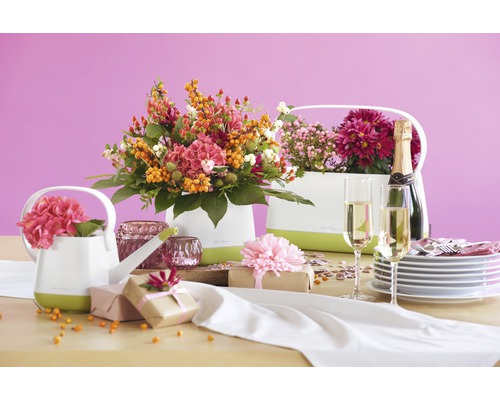 Decoratieve tafel met bloemstukken in sierpotten, cadeaus, champagne en servies