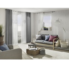 Woonkamer met bank, fauteuil, gordijnen en decoratieve elementen voor een gezellige sfeer.