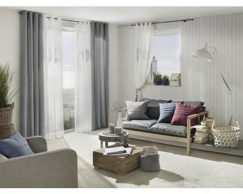 Woonkamer met bank, fauteuil, gordijnen en decoratieve elementen voor een gezellige sfeer.