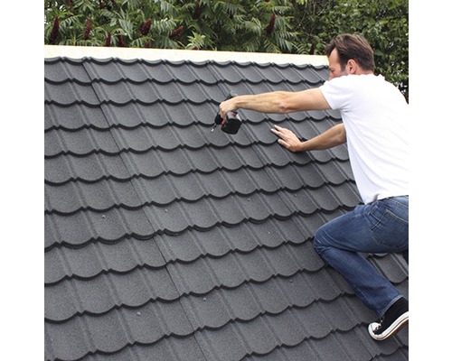 Ambachtsman monteert metalen dakpannen met een accuschroevendraaier