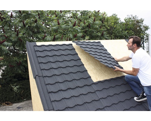 Man legt metalen dakpannen op een dak.