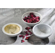 Drie betonnen schalen, één belegd met goud, één gevuld met rozenblaadjes, één leeg.