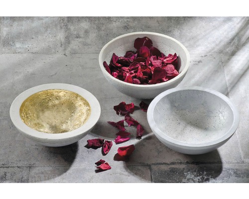 Drie betonnen schalen, één belegd met goud, één gevuld met rozenblaadjes, één leeg.