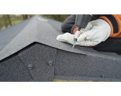 Een persoon bevestigt dakshingles met een schroevendraaier.