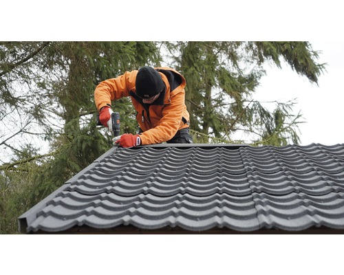 Ambachtsman monteert dakpannen met een accuschroevendraaier
